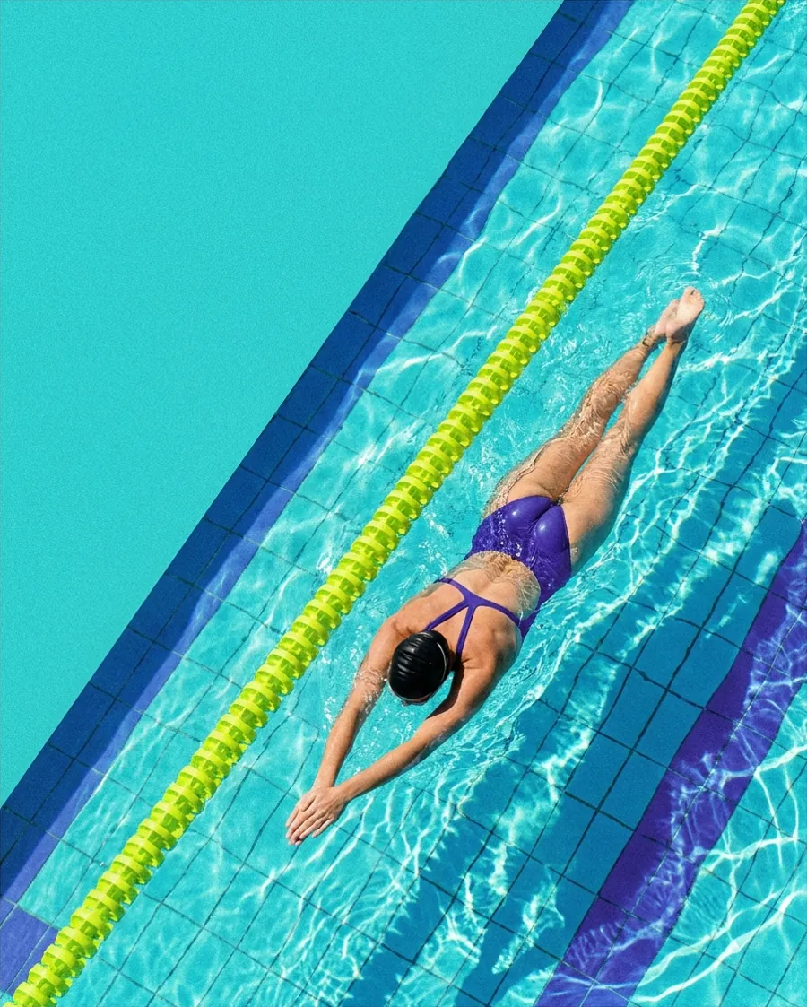 Swimmer seen from above in a turquoise pool next to a lime green lane rope